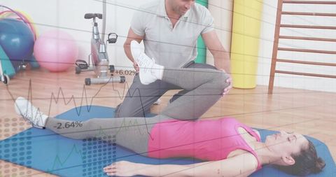 Physiotherapist assisting female client with leg stretch on mat