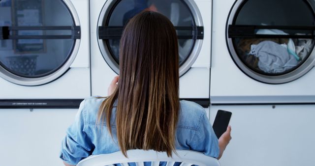 Woman Using Smartphone While Waiting at Laundromat - Download Free Stock Images Pikwizard.com