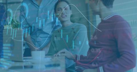 Team collaborating over data visualization with candlestick graphs and laptop