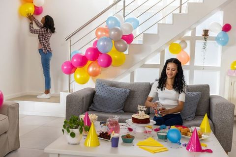 Mother and teen daughter decorating home with colorful balloons for birthday celebration