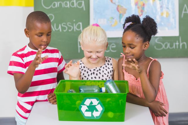 Diverse group of school children gathered around a green recycling bin filled with plastic bottles, engaging in an educational activity about recycling and sustainability. Ideal for use in educational materials, environmental campaigns, school programs, and articles promoting eco-friendly practices and environmental awareness.