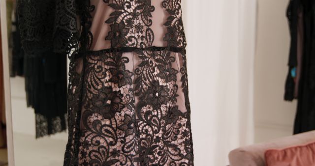 Close up of a black lace dress with pink underlay displayed on a mannequin in a fashion boutique, slow motion