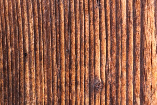 Close-up of rough wooden surface showcasing vertical grain pattern, commonly used for backgrounds, natural texture projects, rustic-themed designs, or environmental presentations.