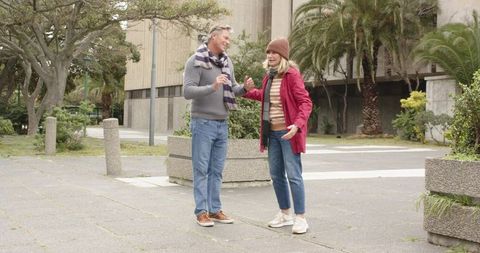 Mature couple enjoying urban walk and conversation near planters and modern architecture