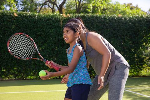 Tennis Instructor Guides Child on Court for Skill Building