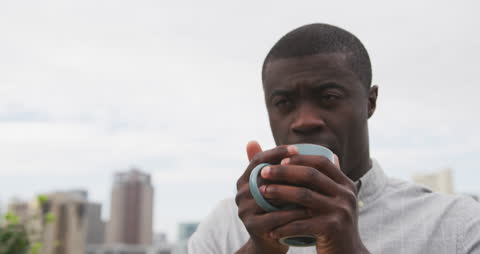 Pensive Man Drinking Coffee on Urban Rooftop