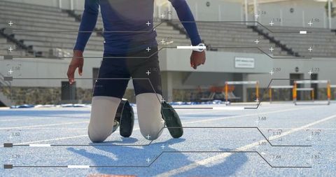 Kneeling sprinter preparing for race on blue track wearing spiked shoes and smartwatch