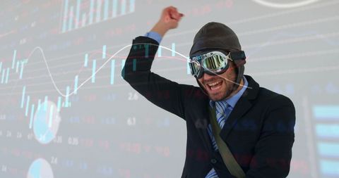 Executive celebrating stock market win wearing aviator goggles, cheering, financial charts