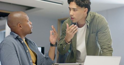 Two diverse male coworkers debating project ideas while collaborating in modern casual office