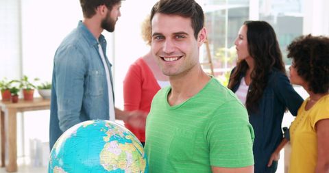 Young professional holding globe in multicultural workplace
