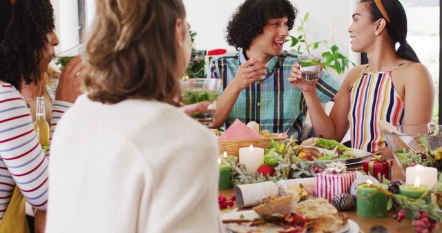 Friends sitting at table having joyful conversation while sharing a festive meal during holiday gathering. Can be used in contexts related to holiday parties, meal gatherings, friendship, celebration, and festive occasions.