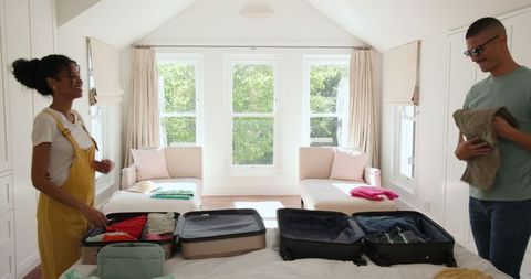 Couple Packing for Vacation in Bright Modern Bedroom