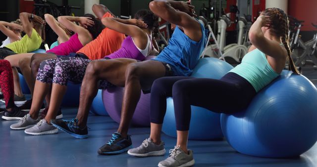 People taking a group fitness class using exercise balls in a gym. Good for illustrating concepts related to physical fitness, group training sessions, health and wellness programs, and active lifestyles. Can be used in fitness articles, health blogs, promotional materials for gyms, and even as a motivational image for exercise routines.