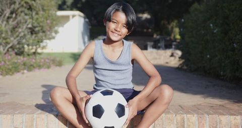 Youthful Boy Enjoying Outdoors with Soccer Ball in Sunny Backyard
