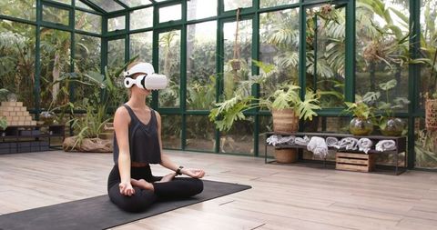 Woman Meditating with VR Headset in Modern Glasshouse Studio