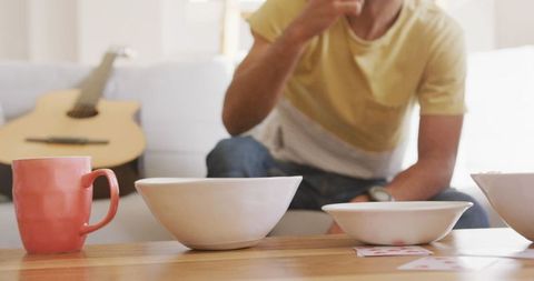 Image depicts a relaxed and casual gathering of friends at home during the weekend. Focused on a cozy setting with snacks in bowls on a wooden table and a guitar in the background. This picture can be used to represent leisure activities, socializing, and bonding among friends. It is ideal for use in lifestyle blogs, social advertisements, or artistically designed posters to highlight themes of friendship, weekend enjoyment, or home relaxation.