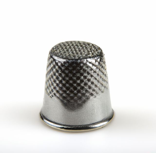 Image of close up of silver thimble and copy space on white background. Clothing, sewing and tailoring concept.