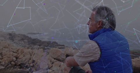 Senior Man in Blue Vest Overlooking Ocean with Digital Overlay Effects