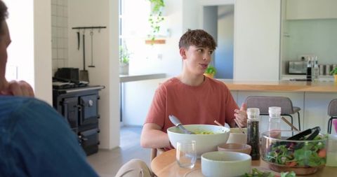 Teenage boy enjoying casual family meal in bright modern open-plan kitchen