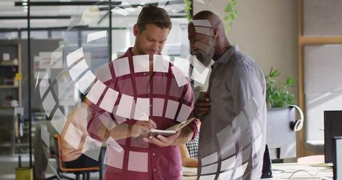 Colleagues reviewing notes and collaborating in modern open office with glass partition