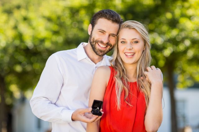 Portrait of happy couple holding ring standing in the park