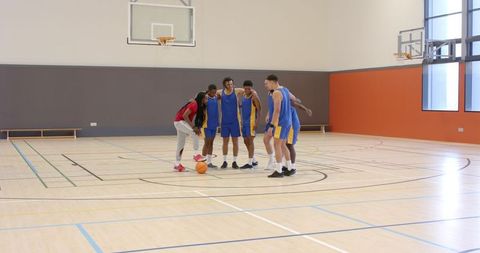 Coach Mentors Basketball Team in Gym During Training Session