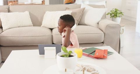Child learning on tablet with headphones in bright modern living room for e-learning