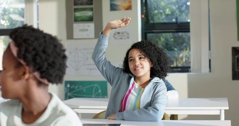 African American Teen Girl Raising Hand in Classroom with Tablet and Colorful Hoodie