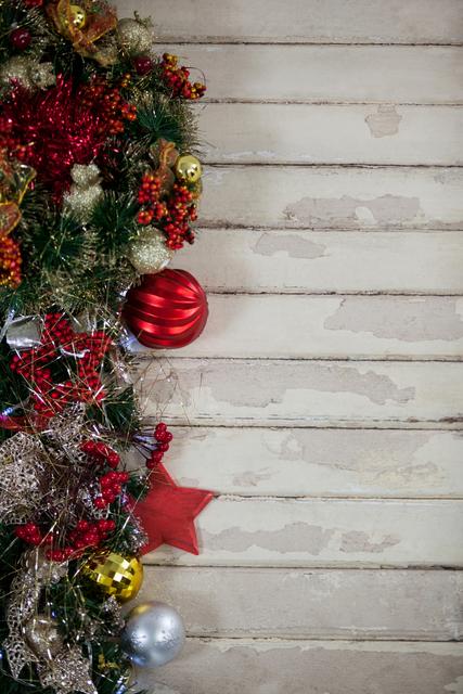 This image captures a close-up view of vibrant Christmas decorations arranged on a rustic wooden plank. The decorations include red, gold, and silver baubles, pine branches, and other festive ornaments. Ideal for holiday-themed marketing materials, greeting cards, social media posts, and seasonal advertisements.
