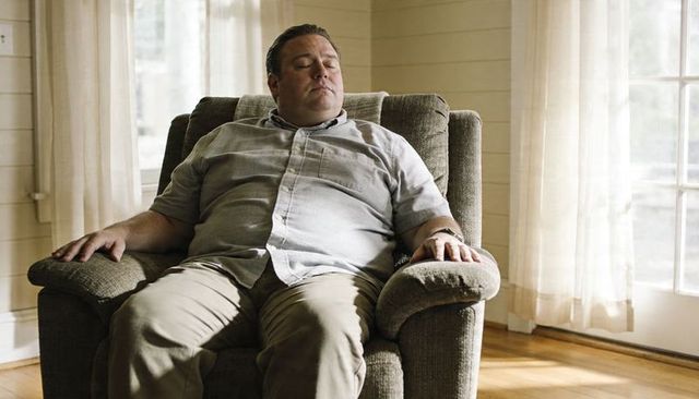 Middle-aged man relaxing in recliner at home, midday sunlight, calm living room moment