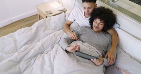 Cozy Couple Relaxing in Bed Using Tablet at Home
