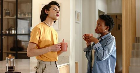 Young man and african american woman enjoying coffee and conversation in cozy kitchen