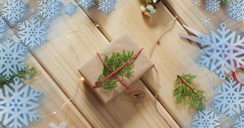 Rustic kraft wrapped gift with red twine and evergreen sprig flat lay for holidays