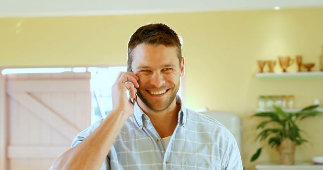 Smiling Young Man Talking on Smartphone in Bright Room - Download Free Stock Images Pikwizard.com