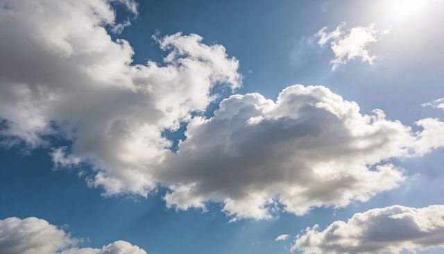 Sunlit Cumulus Cloudscape Over Blue Sky Showing Rays and Airy Texture