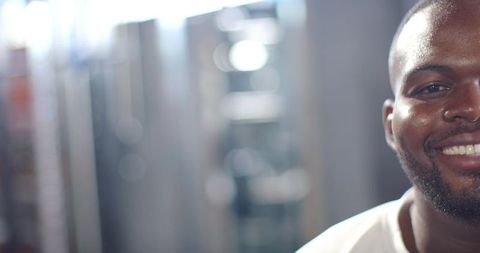 Smiling african american man in white tee with bokeh background, friendly corporate headshot