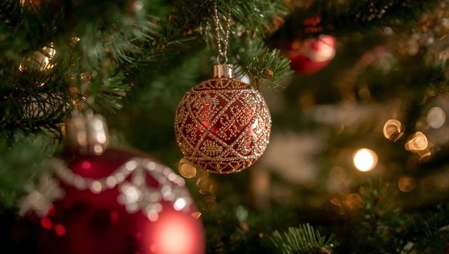 Elegant Red and Gold Christmas Bauble on Tree Branch with Warm Bokeh