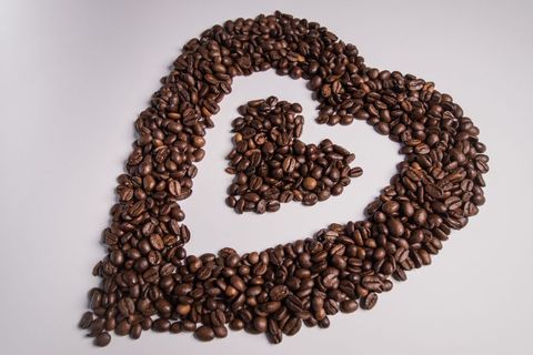 Heart shape made of roasted coffee beans on white background