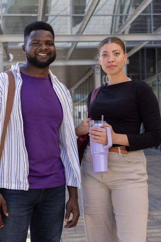 African american students standing on campus plaza holding tumbler and backpacks