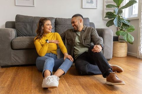 Young couple relaxing on living room floor smiling and connecting in cozy modern home