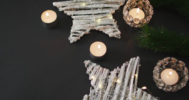 Various Christmas decorations featuring lit candles and star-shaped ornaments arranged on a dark background. This setup evokes a cozy and festive holiday mood, suitable for Christmas greeting cards, holiday marketing materials, or home decor inspiration.