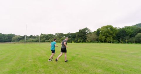 Men jogging on lush green field for fitness enjoyment