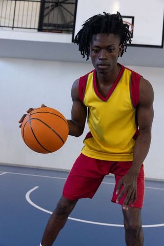 Athletic Man Dribbling Basketball on Indoor Court with Intense Focus