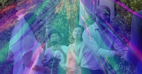 Bride holding bouquet while guest recording garden ceremony with rainbow lensflare