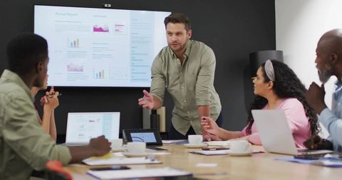 Presenting team in boardroom analyzing charts and slides during collaborative meeting