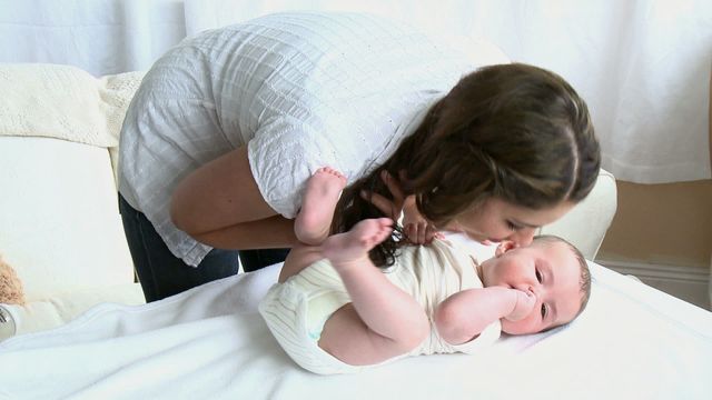 Young mother showing affection for her baby in a comfortable home nursery. Useful for parenting blogs, family-oriented advertisements, baby care products promotions, or any materials featuring maternal love and childcare.