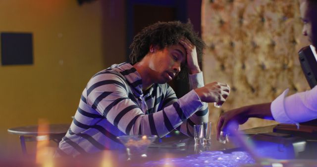 Image of hands of african american barman serving and drunk man sitting drinking shots at the bar. Drinking, going out and alcohol concept.