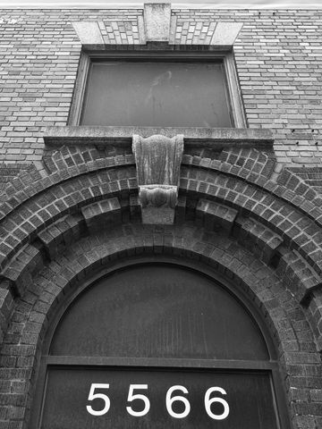 Showcasing ornate brick arch and keystone above arched doorway with address 5566