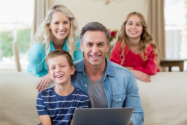Portrait of smiling parents and kids with laptop in living room at home