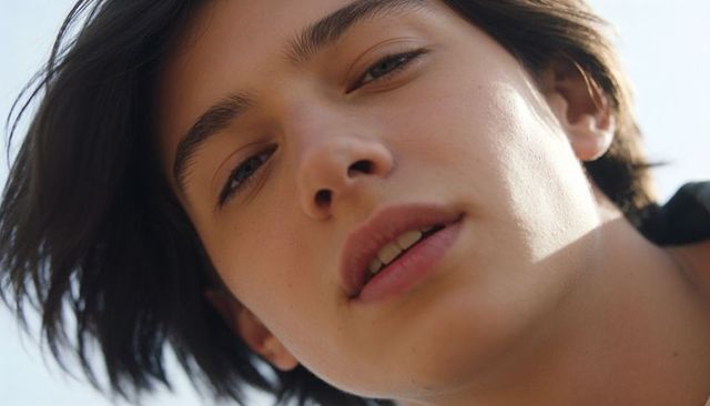 Intimate closeup headshot of teen male with windswept dark hair and soft daylight